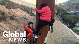 Migrant families continue to spill over Tijuana border fence head to US [upl. by Kanor]